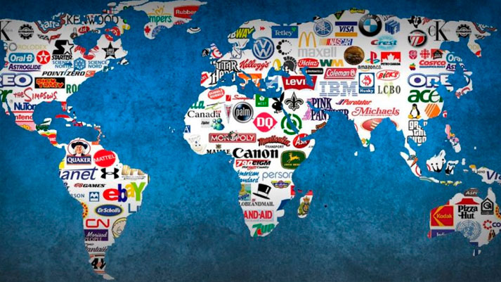 Um mapa-múndi estilizado com o contorno dos continentes preenchido com uma colagem de logotipos de várias marcas globais conhecidas, representando a presença e o desafio da contabilidade em empresas multinacionais que operam em diferentes regiões do mundo.