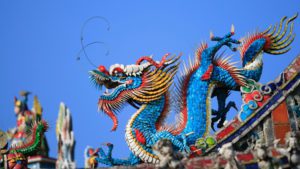 Estatua colorida de um dragão em telhado cerâmico, representando arte e cultura chinesas, destacada no tópico 'Busque parceiros e vantagens para a produção' do post '5 dicas para enfrentar a concorrência das indústrias chinesas'.