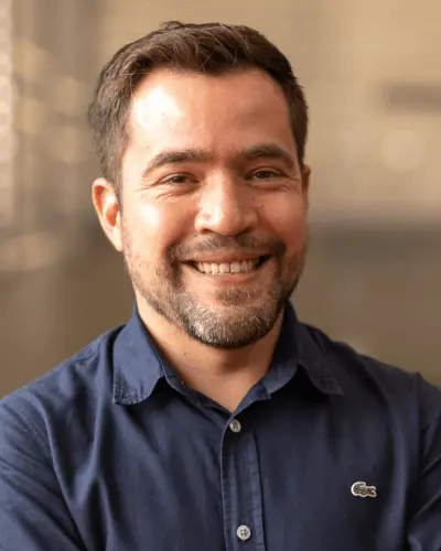 Sócio-Fundador Jonas Oliveira sorridente, vestindo camiseta social azul escura.