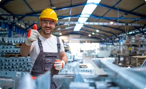 Trabalhador sorridente com equipamento de segurança em um ambiente industrial, representando as soluções contábeis da OSP para o setor de indústrias.