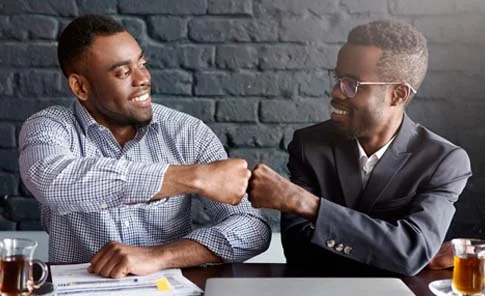 Dois empresários comemorando um acordo com um toque de punho, representando a colaboração estratégica oferecida pela OSP Soluções Contábeis no segmento de Lucro Real.