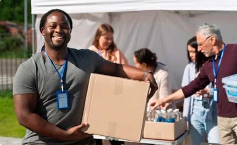 Voluntário sorridente carregando uma caixa de doações, simbolizando o suporte contábil da OSP para organizações do Terceiro Setor.