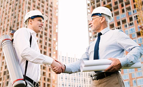 Dois engenheiros de construção civil cumprimentando-se em um canteiro de obras, ilustrando o compromisso da OSP Soluções Contábeis em estabelecer parcerias sólidas e oferecer serviços contábeis especializados para o setor.