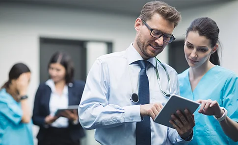 Médicos consultando um tablet em hospital, refletindo os serviços contábeis da OSP para médicos e profissionais da saúde.