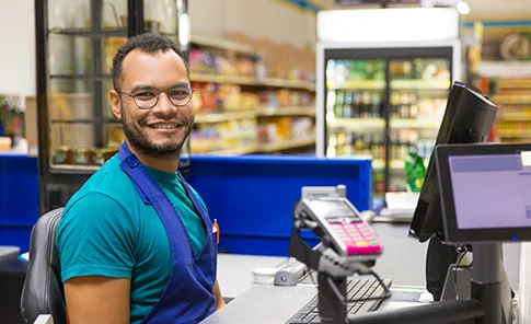 Funcionário de supermercado com sorriso amigável no caixa.